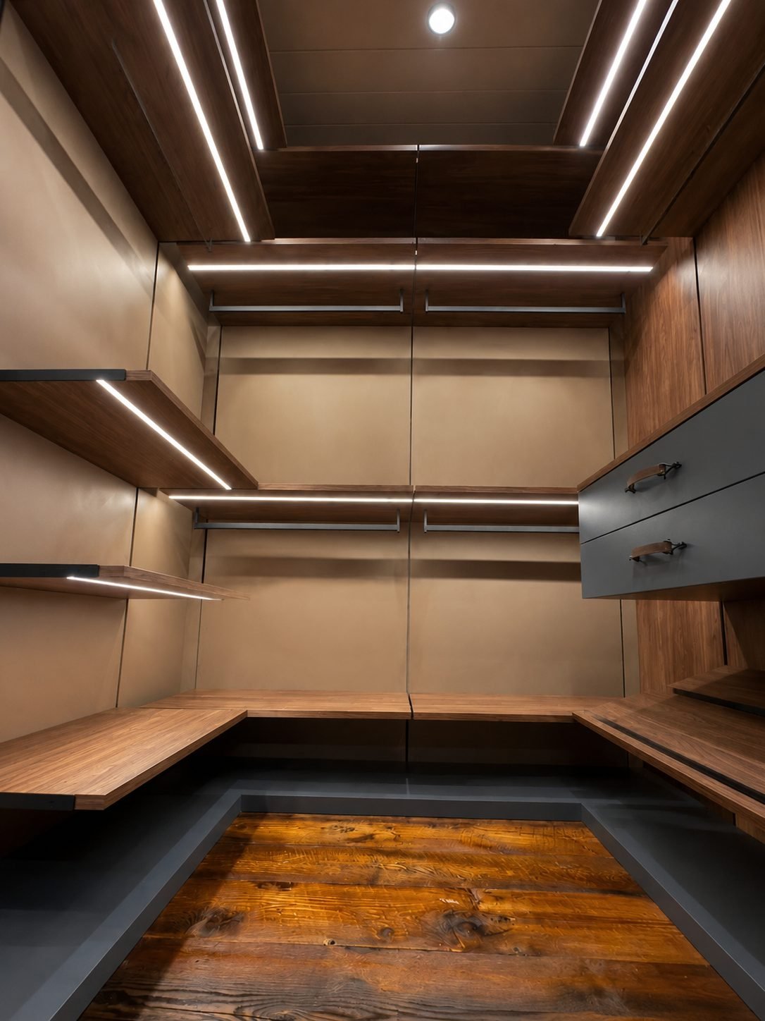 Walnut closet corner with slate-blue drawers, leather hardware and a reclaimed wood floor patch under linear LED lighting